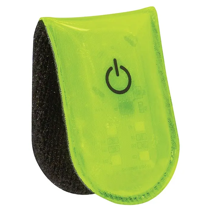 Abus LED-Leuchte Linus - Gelb - Nahaufnahme eines grünen LED-Sicherheitsblinklichts mit Klettverschluss und einem schwarzen Ein/Aus-Symbol auf schwarzem Hintergrund.