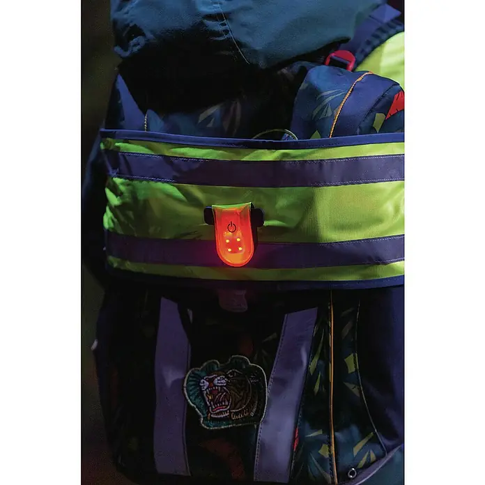 Abus LED-Leuchte Linus - Gelb - Nahaufnahme eines Rucksacks mit reflektierenden Streifen und einem LED-Sicherheitslicht für bessere Sichtbarkeit bei Dunkelheit.