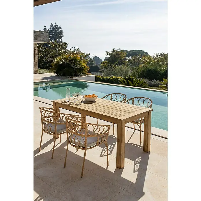 Silla de jardín Marius - Natural, Ratán sintético - Una mesa de comedor rectangular de madera con cuatro sillas se encuentra junto a la piscina, invitando a comidas al aire libre.