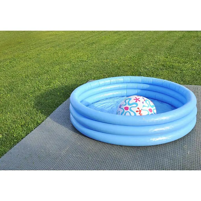 Klickfliese - Polyethylen, 55,5 x 55,5 x 1,1 cm, Grau, 9 Stk. - Das Bild zeigt ein blaues Planschbecken mit einem bunten Ball im Wasser auf einer grauen Unterlage, vor einem grünen Rasen.