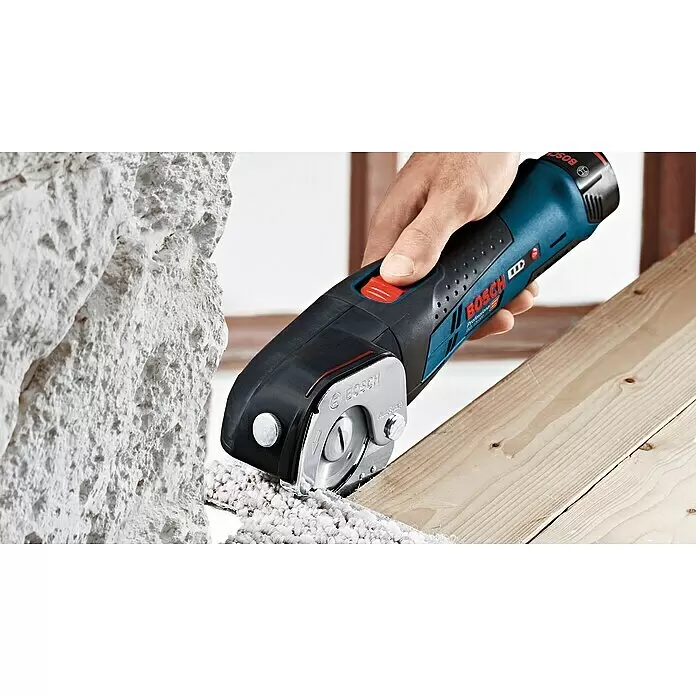 Bosch Professional Akku-Universalschere GUS 12V-300 - 12 V, Ohne Akku, Leerlaufhubzahl: 700 /min - Eine Hand hält einen blau-schwarzen Bosch Akku-Schneider, dessen Kreisklinge beigen Teppich auf Holz schneidet.