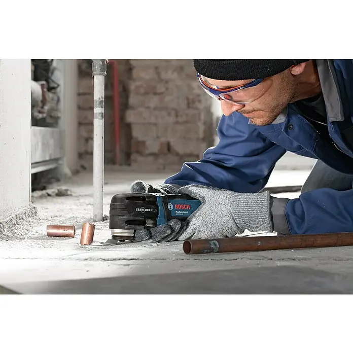Bosch Professional Elektro-Multifunktionswerkzeug GOP 30-28 - 300 W, STARLOCK-Plus-System - Der Handwerker benutzt einen Bosch Professional GOP 30-28 Multifunktionsschneider, um ein Rohr zu schneiden. Schutzkleidung wird getragen.