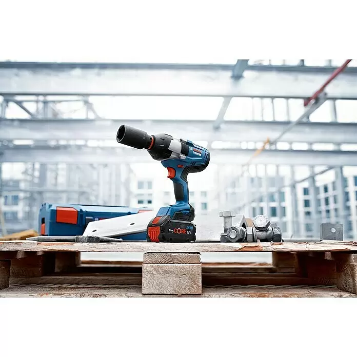 Bosch Professional AMPShare 18V Akku-Drehschlagschrauber GDS 18V-1050 H - 18 V, Ohne Akku - Blauer und schwarzer Bosch Akku-Schlagschrauber mit schwarzem Bit und ProCORE 18V Akku auf Holzpalette auf Baustelle.