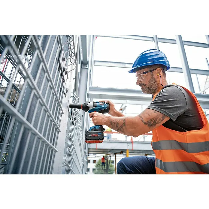 Bosch Professional AMPShare 18V Akku-Drehschlagschrauber GDS 18V-1050 H - 18 V, Ohne Akku - Mann mit Bosch Akku-Schlagschrauber bei der Arbeit, schraubt eine Schraube in ein Metallgitter. Schutzkleidung wird getragen.