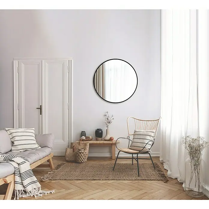 DSK Wandspiegel Silver Coiffeur - Durchmesser: 80 cm, Schwarz - Das Foto zeigt einen stilvollen Raum mit einem runden Spiegel an der Wand, einem Teppich und einem Korbstuhl, der ein gemütliches Ambiente schafft.