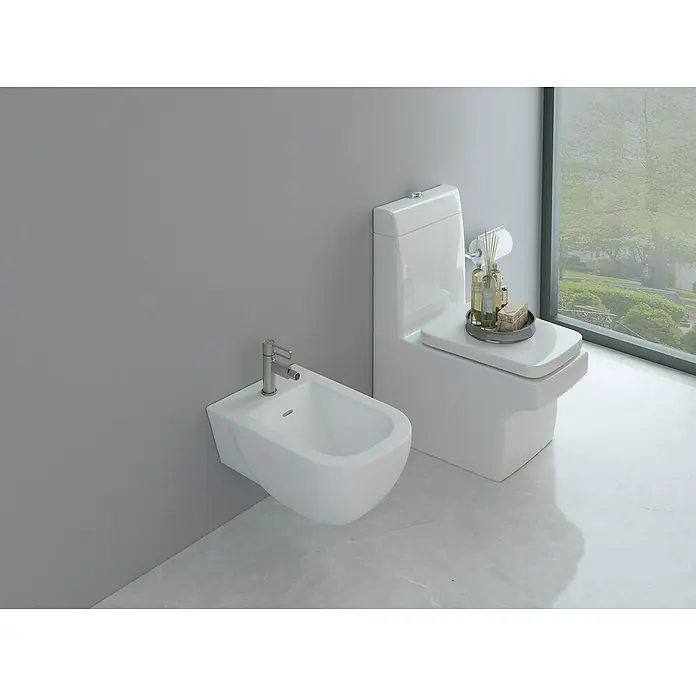 IO Dior Grifo monomando de bidé - Titanio - La imagen muestra un inodoro moderno con un bidé en un baño con paredes grises y suelo de mármol. El bidé tiene un grifo cromado.