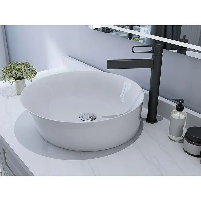 IO Dior Grifo de lavabo alto - Negro - Primer plano de un baño moderno con un lavabo redondo, grifo y artículos de tocador sobre una encimera de mármol.
