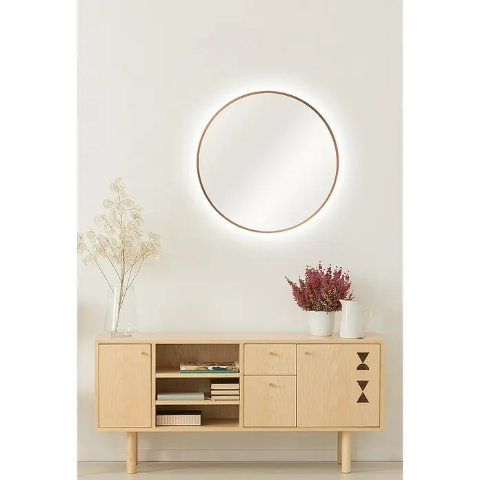 DSK Lichtspiegel Silver Barbier - Durchmesser: 50 cm, Kupfer, Leuchtmittel - Dekorativer runder Wandspiegel mit Lichteffekt und ein modernes Sideboard aus hellem Holz mit Blumen und Vasen darauf.