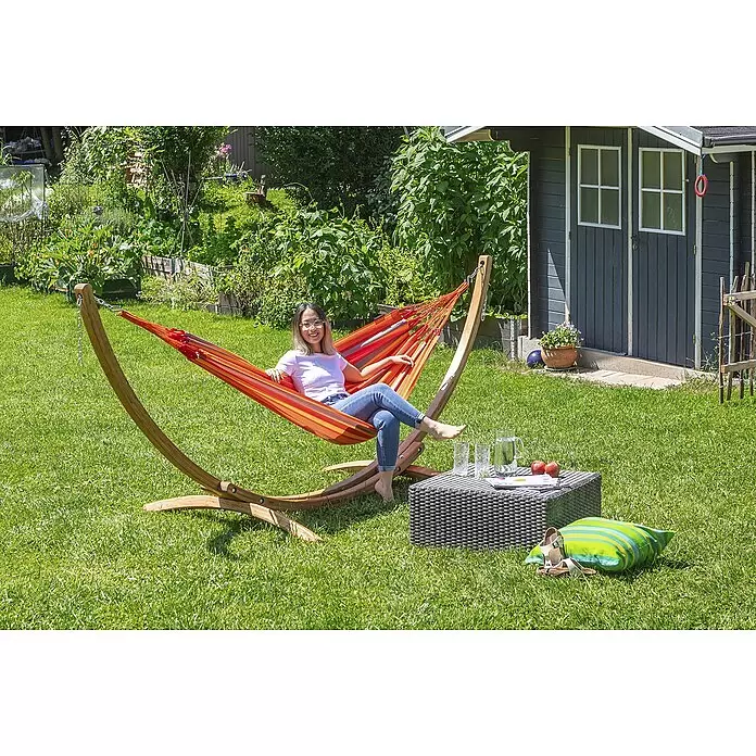La Siesta Hängematte Brisa - L x B: 300 x 140 cm, Toucan - Frau entspannt sich in einer bunten gestreiften Stoffhängematte mit Holzständer, draußen aufgestellt.