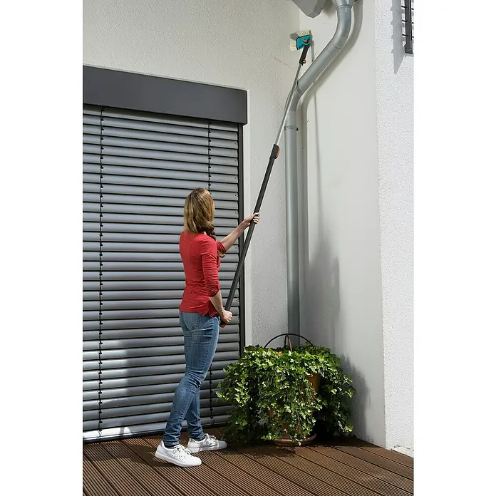 Gardena Combisystem Winkelbesen - Passend für: Alle Gardena Combisystem-Stiele, Kunststoff - Frau reinigt Dachrinne mit Gardena Reinigungsbürste. Die Bürste hat einen Teleskopstiel für hohe Reichweite.
