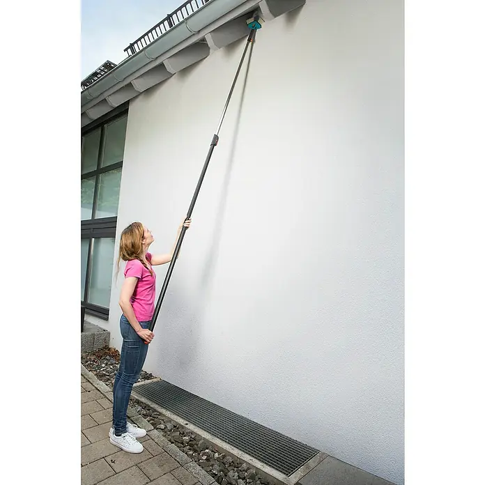 Gardena Combisystem Winkelbesen - Passend für: Alle Gardena Combisystem-Stiele, Kunststoff - Eine Frau reinigt mit einem Teleskopstiel und Bürste eine Dachrinne. Das Werkzeug erleichtert die Gartenarbeit und Reinigung im Außenbereich.
