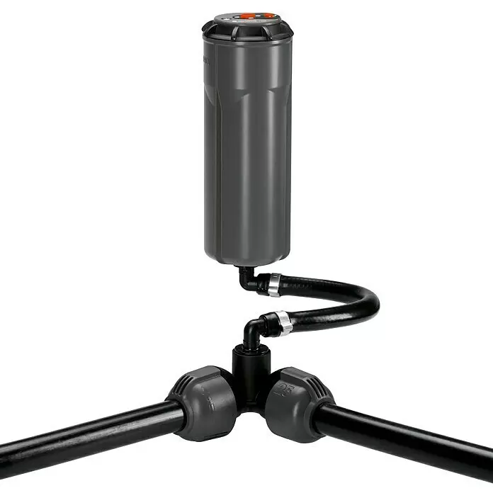 Gardena Sprinklersystem Winkelstück - Durchmesser: 25 mm, Größe Anschluss: ¾″ (Innengewinde) - Dunkelgrauer Versenkregner, über schwarzen Flexschlauch an ein T-Stück angeschlossen, das Wasser an schwarze Rohre verteilt.