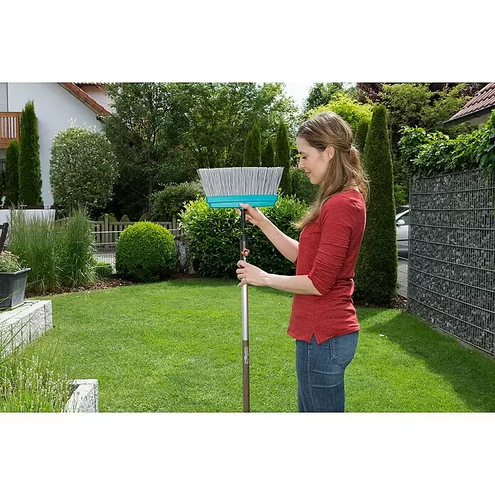 Gardena Combisystem Terrassenbesen - Material Borsten: Kunststoff, Arbeitsbreite: 32 cm - Frau montiert einen türkisen und grauen Gartenbesen mit verstellbarem Silberstiel.