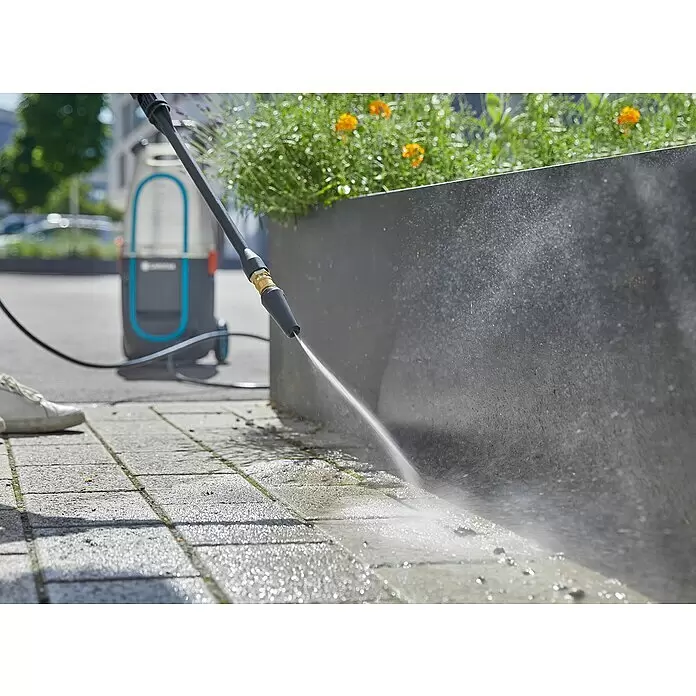 Gardena Rotationsdüse AquaClean - Passend für: Gardena Hochdruckreiniger AquaClean Li-40/6 - Hochdruckreiniger säubert Pflastersteine neben einem dunklen Pflanzgefäß. Das grau-blaue Gerät ist im Hintergrund.