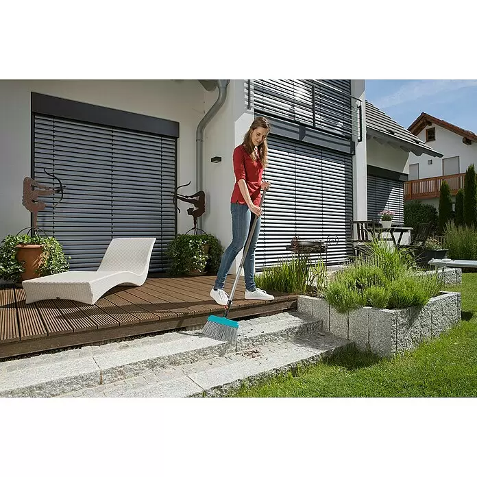 Gardena Combisystem Terrassenbesen - Material Borsten: Kunststoff, Arbeitsbreite: 32 cm - Eine Frau kehrt eine Terrasse und Steinstufen mit einem blau-grauen Besen.