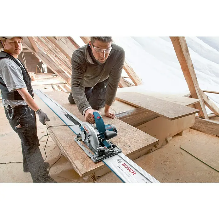Bosch Professional Handkreissäge GKS 65 GCE - 1.800 W, Durchmesser Sägeblatt: 190 mm, Schnitttiefe bei 90 °: 65 mm - Zwei Bauarbeiter beim Zuschneiden von Holz mit einer Bosch Tauchsäge auf einer Baustelle, wobei die Präzision und Effizienz des Werkzeugs im Vordergrund stehen.