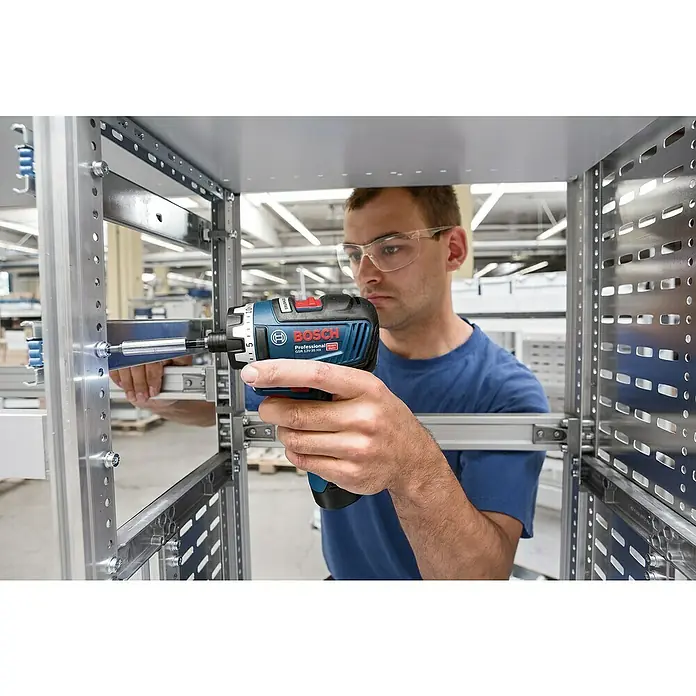 Bosch Professional AMPShare 18V Akku-Bohrschrauber-Set GSR 12V-35 HX PRO SOLO - 12 V, Ohne Akku, 35 Nm, 4 -tlg. - Ein Handwerker arbeitet mit dem Bosch Professional GSR 12V-35 HX Akku-Bohrschrauber an einem Metallrahmen. Er trägt dabei eine Schutzbrille.