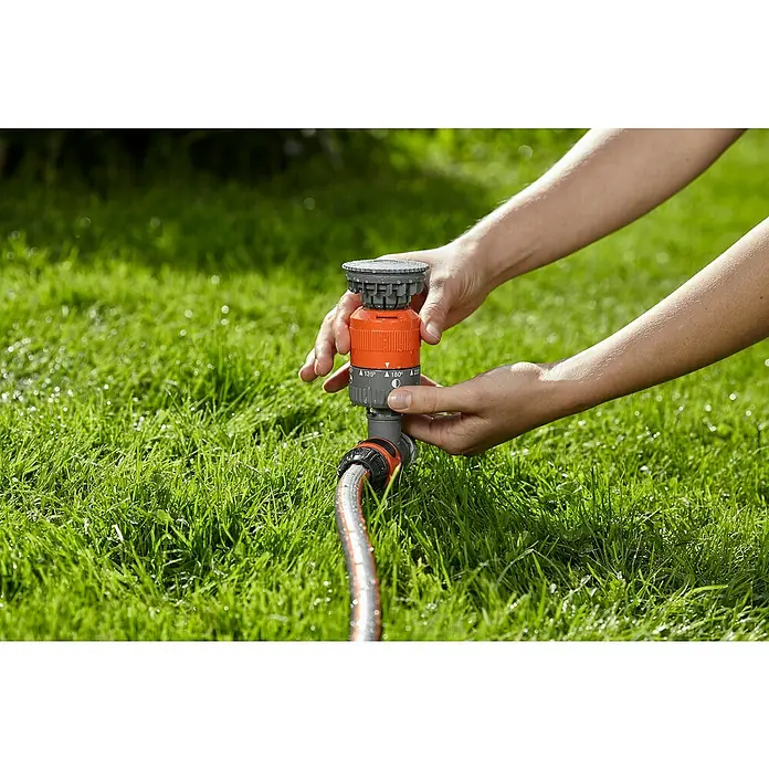 Gardena Comfort Kreisregner Vario - Erdspieß, Max. Regnerfläche: 225 m² - Eine Person stellt einen GARDENA Vielflächenregner auf einem grünen Rasen ein, um den Garten optimal zu bewässern.