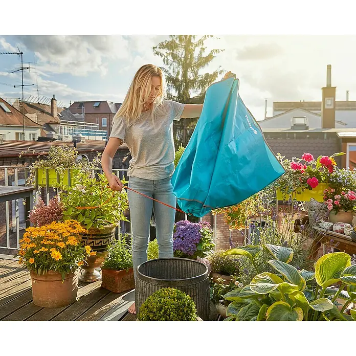 Gardena Formschnittmatte City Gardening - L x B: 150 x 150 cm - Eine Frau, die einen Gardena-Gartensack auf einem Balkon mit Topfpflanzen hält.