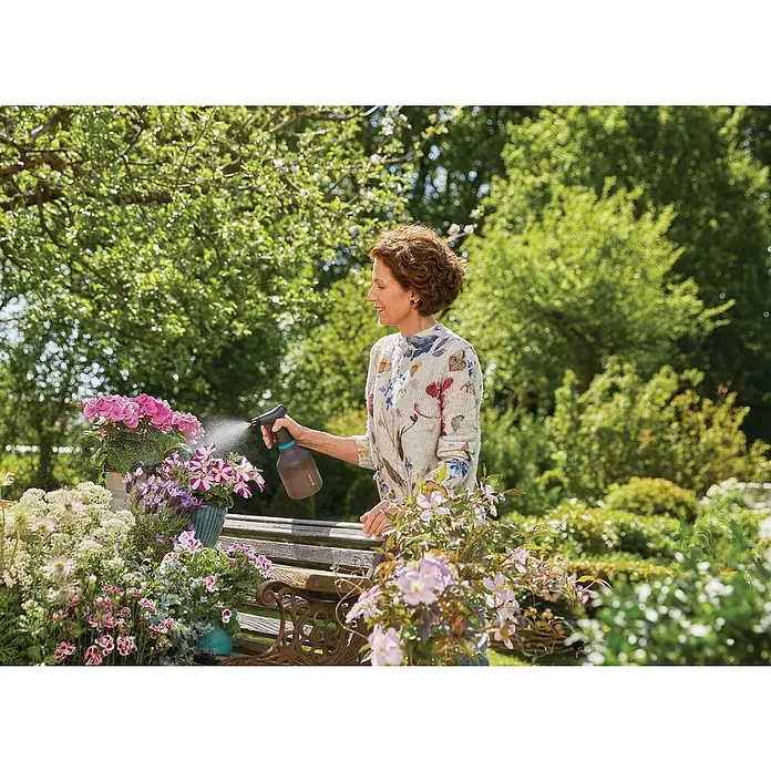Gardena Drucksprüher Set - Bestehend aus: Drucksprüher Comfort 5 l & Pumpsprüher 0,75 l - Frau, die Blumen mit einer GARDENA-Sprühflasche gießt, wobei die Sprühflasche im Mittelpunkt steht.