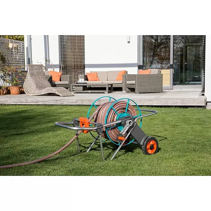 Gardena Schlauchwagen 100 - Metall, Schlauchkapazität: 100 m, 13 mm (1/2") - Gardena Schlauchwagen mit grauem und orangefarbenem Schlauch auf grünem Rasen vor einer Terrasse.