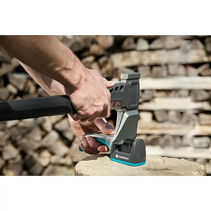 Gardena Axt- & Messerschärfer - Länge: 190 mm - Person schärft ein Beil mit einem grau-türkisen Gardena Beilspitzer auf einem Holzstumpf.