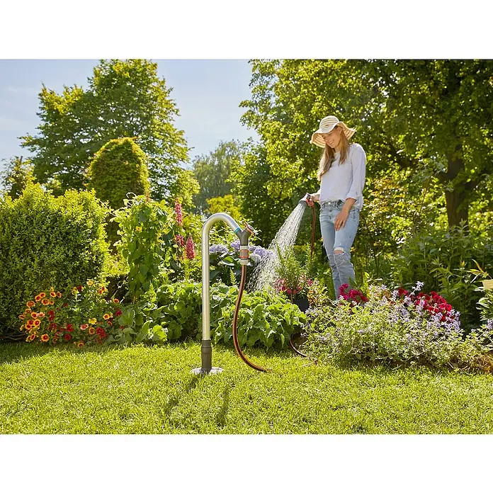 Gardena Sprinklersystem Wasserhahn - Metall - Frau gießt Blumen mit einer Gardena Regendusche im Garten. Das System ist praktisch und leicht zu bedienen für die Gartenbewässerung.