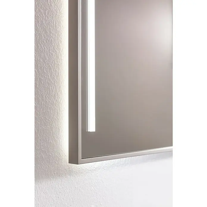 Camargue Marea Badmöbel-Set - Gesamtbreite Badmöbel: 60 cm, Goldbronze - Nahaufnahme eines beleuchteten Spiegels an einer strukturierten Wand, der ein modernes und elegantes Design aufweist.