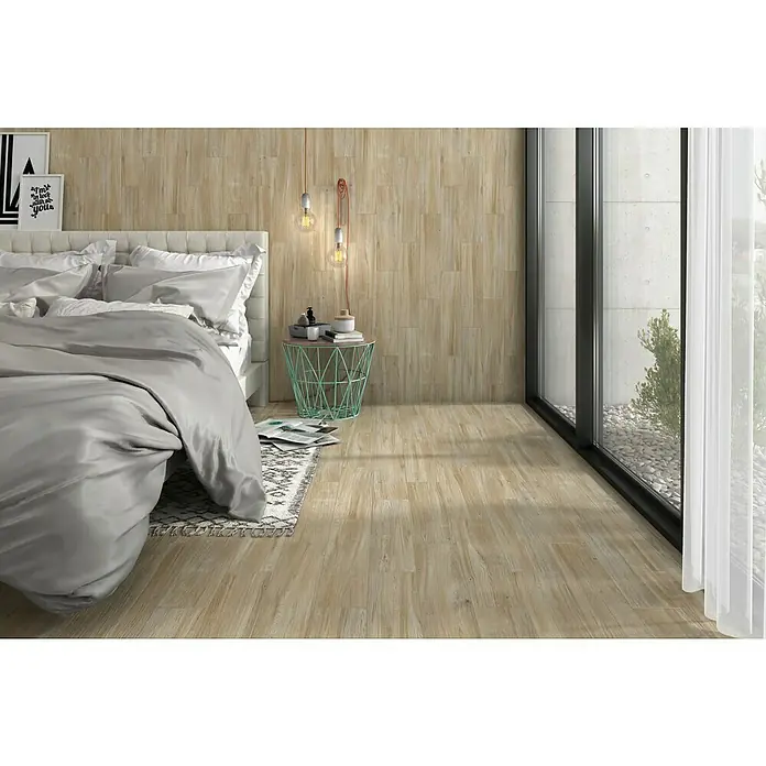 Pavimento porcelánico Baltimore - 120 x 23,3 cm, Beige, Mate - Dormitorio luminoso con suelo de imitación madera y pared decorativa, creando un ambiente cálido y acogedor. La gran ventana deja entrar luz natural.