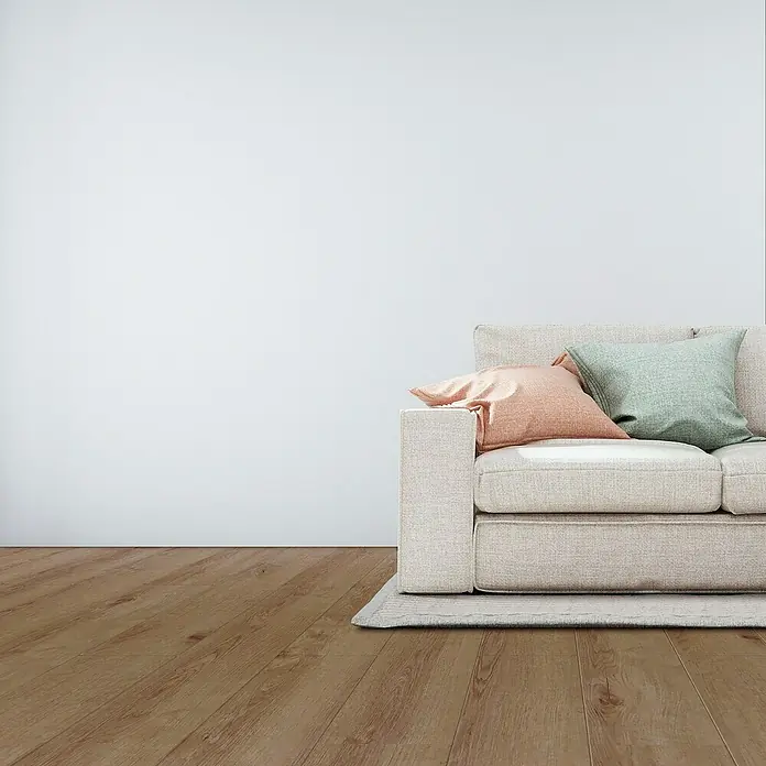 Suelo vinílico SPC Roble Baeza - 1.220 x 180 x 5,5 mm, Marrón, Resistente al agua - Cómodo sofá claro con cojines en una habitación luminosa, ideal para relajarse. Crea un ambiente acogedor.