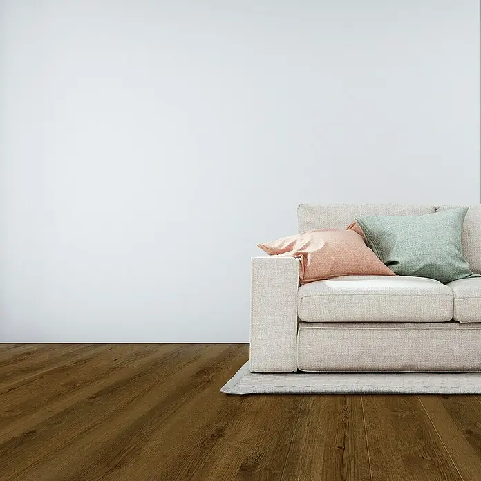 Suelo vinílico SPC Roble Braga - 1.220 x 180 x 5,5 mm, Marrón, Resistente al agua - Sofá luminoso con cojines en una habitación con suelo de madera, creando un ambiente acogedor.