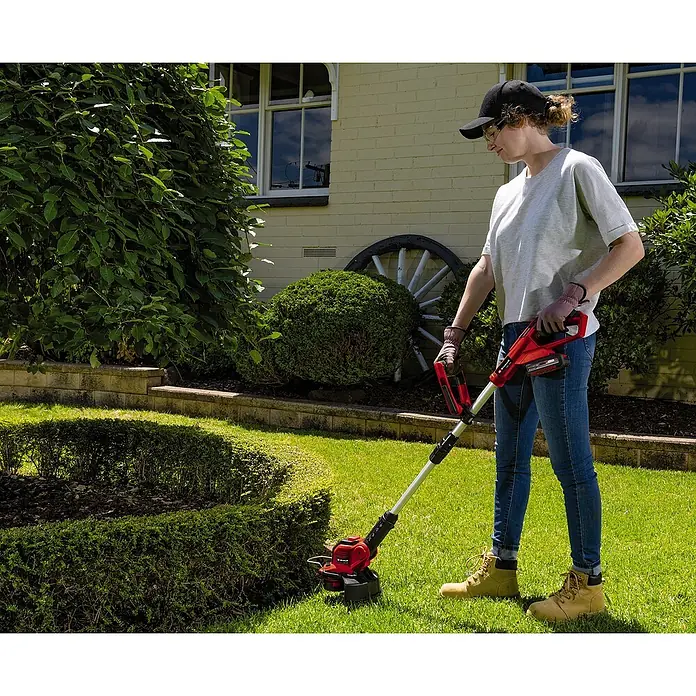 Einhell Power X-Change 18V Akku-Rasentrimmer GE-CT18/28LI TC-Solo - 18 V, Li-Ionen, Ohne Akku, Schnittbreite Faden: 28 cm - Frau arbeitet mit einem Einhell Akku-Rasentrimmer im Garten, um präzise Rasenkanten zu schneiden und das Erscheinungsbild zu verbessern.