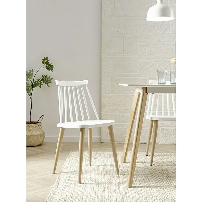 Silla Nova - L x An x Al: 45 x 42 x 78 cm, Blanco - Primer plano de una silla de madera blanca con patas de madera clara sobre una alfombra estampada en una habitación luminosa.