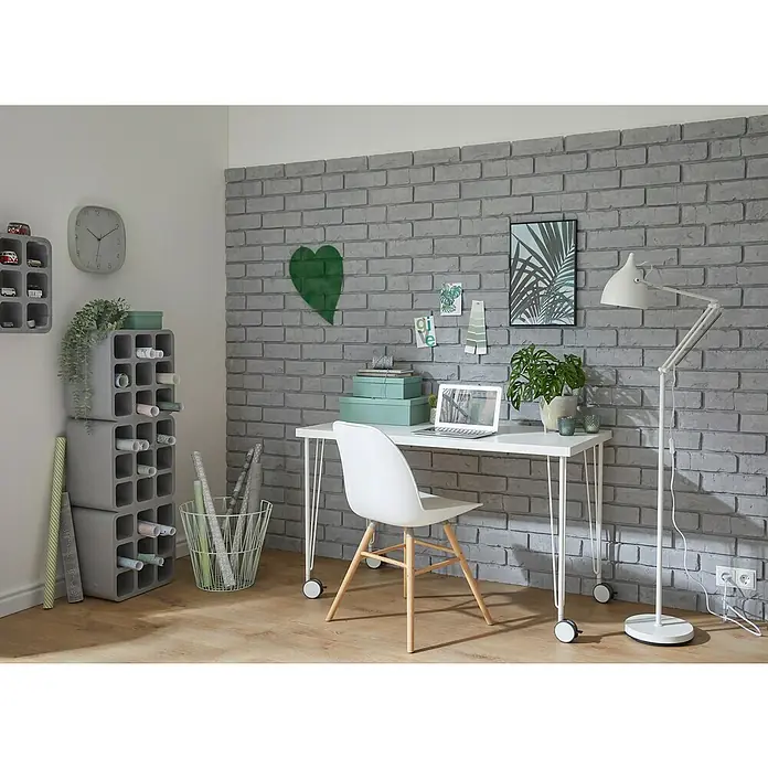 Decosa Masilla de poliestireno placa Ladrillo - 50 x 2,5 x 59,5 cm - Un espacio de trabajo moderno con un escritorio blanco elegante y una silla blanca de estilo, sobre una pared de ladrillos grises.