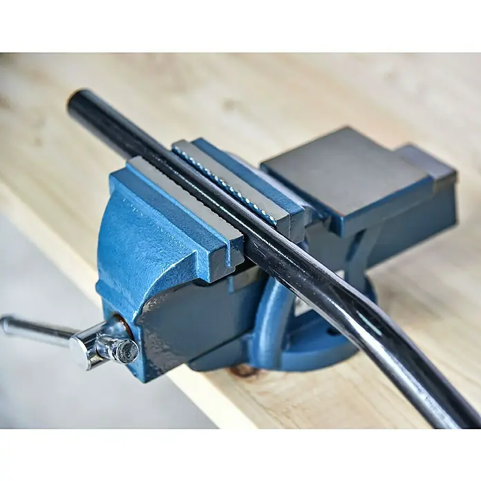 Schraubstock - 100 mm, Feststehend, Metall - Blaue Werkbank mit einem Rohr, das mit einem Schraubstock befestigt ist. Ideal zum sicheren Halten von Werkstücken bei handwerklichen Arbeiten.