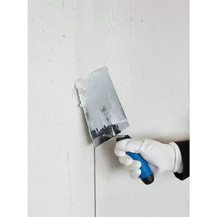 Alpha Tools Kellen-Set - 3 -tlg. - Behandschuhte Hand trägt weißen Spachtelmasse mit einem Spachtel mit blauem Griff auf eine strukturierte Wand auf.