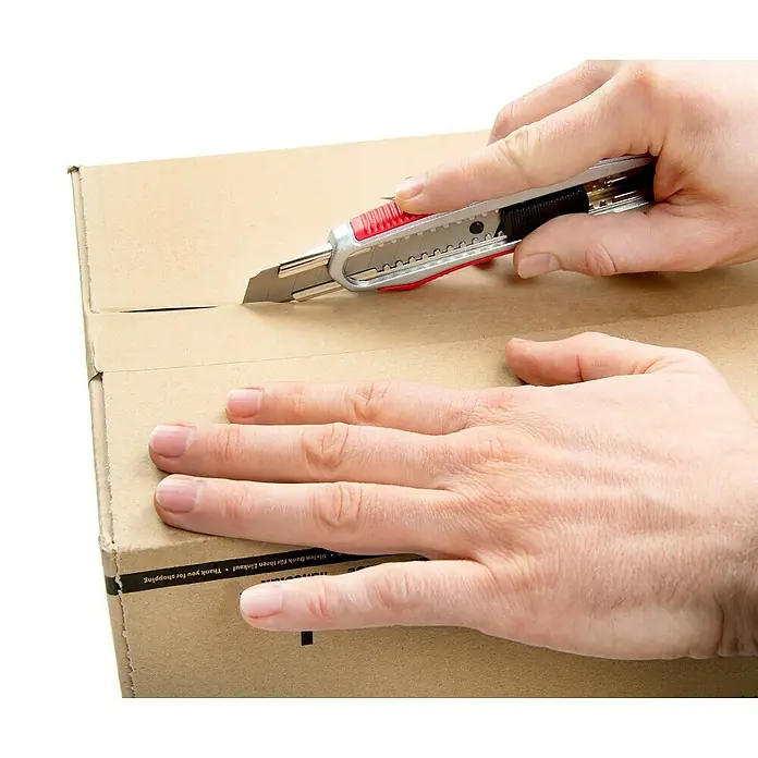 Wisent Cuttermesser - 101 -tlg., Klingenbreite: 18 mm, Silber/Rot - Das Bild zeigt ein Messer, das verwendet wird, um einen Karton zu öffnen, wobei die scharfe Klinge die Pappe durchtrennt.