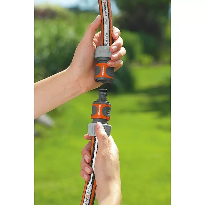 Gardena Schlauchkupplung - Grau - Zwei Hände verbinden einen Gardena Gartenschlauch mit orange-grauen Schnellkupplungen zur einfachen Montage.