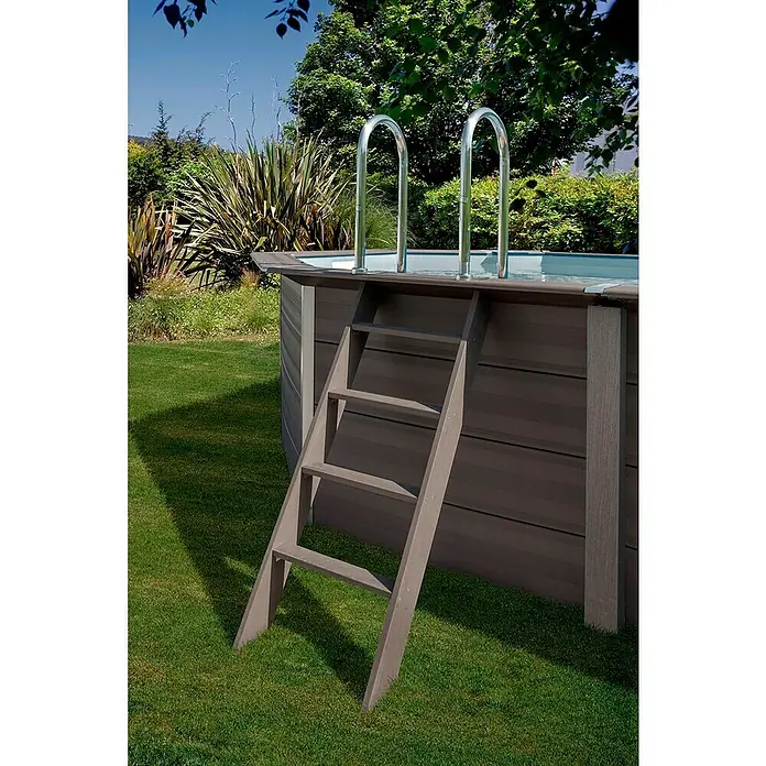 Gre Avantgarde WPC-Pool Avantgarde - L x B x H: 804 x 386 x 124 cm, 27.000 l, Dunkelgrau - Eine Poolleiter führt in einen runden Pool im Garten, umgeben von Rasen und Bäumen.