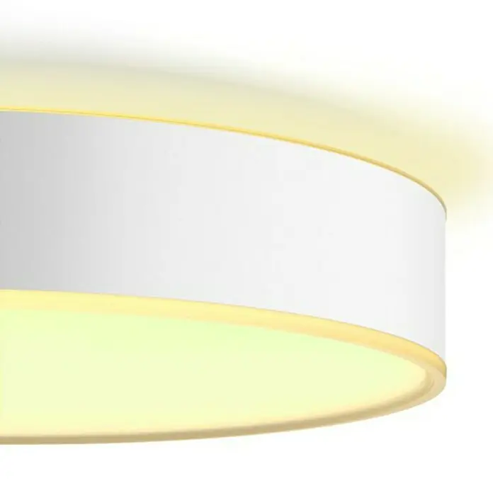 Philips Hue LED-Deckenleuchte rund White Ambience Enrave XL - 48 W, Ø x H: 55,1 x 8,4 cm, Weiß, Kaltweiß - Eine Nahaufnahme einer runden, weißen Deckenleuchte mit gelber Beleuchtung. Das Licht ist warm und diffus.