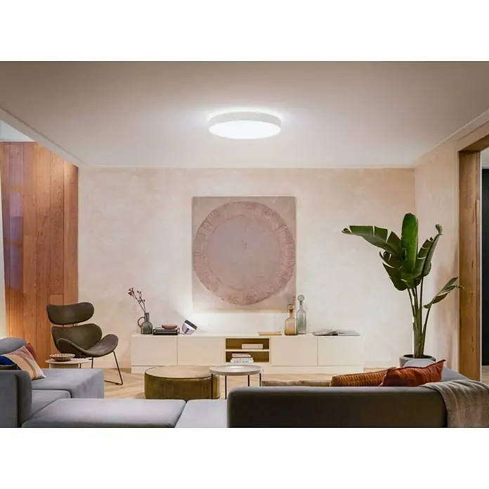 Philips Hue LED-Deckenleuchte rund White Ambience Enrave XL - 48 W, Ø x H: 55,1 x 8,4 cm, Weiß, Kaltweiß - Eine moderne Wohnzimmeransicht mit einer runden Deckenleuchte, die sanftes Licht verbreitet und die zeitgemäẞe Einrichtung hervorhebt.