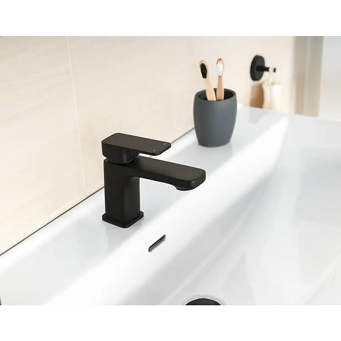 Camargue Waschtischarmatur Marbella - Schwarz, Matt - Nahaufnahme eines modernen, mattschwarzen Wasserhahns auf einem weißen Waschbecken mit minimalistischem Design und zwei Zahnbürsten im Hintergrund.