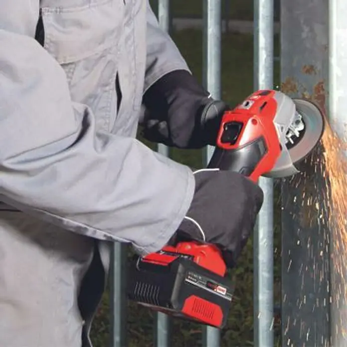 Einhell Amoladora angular de batería TE-AG 18/115 Li - 1 batería, 4 Ah, Diámetro disco: 115 mm - Primer plano de una amoladora angular inalámbrica Einhell en acción, con chispas mientras muele una rejilla metálica. Ideal para proyectos de bricolaje.