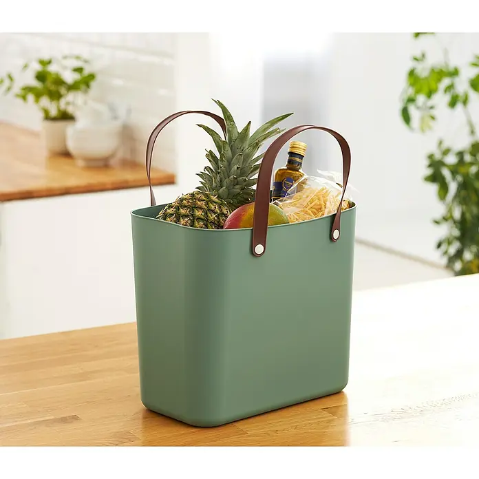 Rotho Albula Tasche Multibag Style - Mistletoe Grün, Kunststoff - Grüne Tragetasche mit Ledergriffen, gefüllt mit einer Ananas, einer Mango, einer Flasche Öl und Nudeln, stehend auf einem Holztisch.