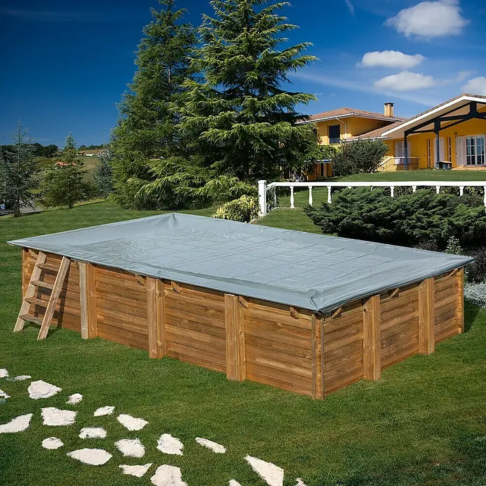 Gre Pool-Abdeckplane Winter EVORA - 658 x 460 cm, Grau - Ein rechteckiger Holzpool mit einer grauen Abdeckung im Garten, umgeben von Grün. Eine Leiter steht an der Seite.