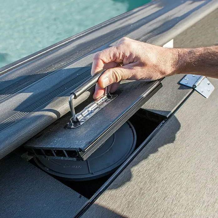 Gre Technikraum für Kompositpools - L x B x H: 80 x 60 x 89 cm, WPC - Detailansicht eines Pooldeckels mit Griff, der geöffnet wird, um den Zugang zum darunter liegenden Mechanismus freizugeben.
