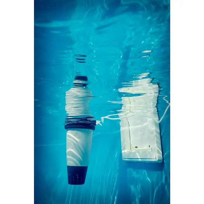 Fluidra Blue Connect Wasser-Analysegerät - Steuerung per Smartphone-App - Unterwasseraufnahme eines Poolchemie-Dosierschwimmers und einer Poolwandleuchte, die im Schwimmbad für sauberes Wasser sorgen.