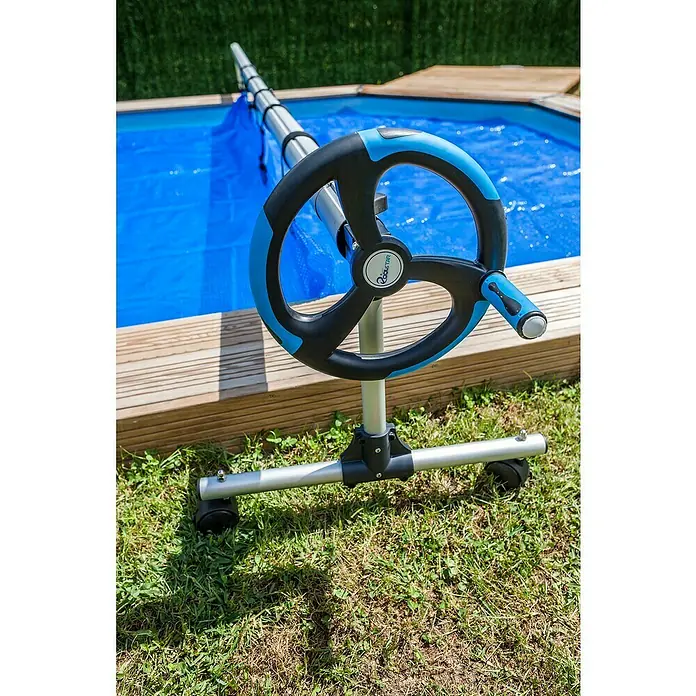 Gre Planenaufroller - Passend für: Pools bis 500 cm Breite - Nahaufnahme einer transportablen Poolabdeckungswickelvorrichtung mit blauer Abdeckung für Schwimmbecken im Hintergrund.
