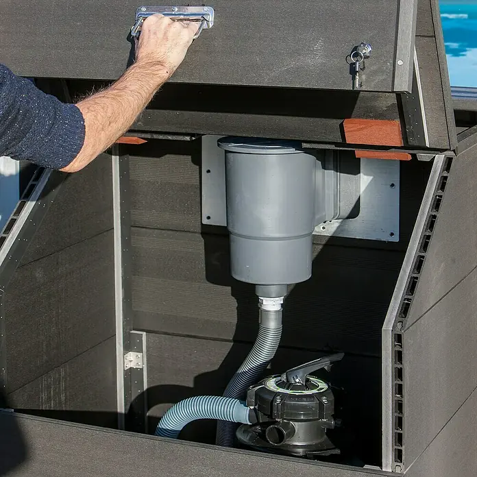 Gre Technikraum - L x B x H: 80 x 60 x 115 cm - Ein Blick in einen Poolfilter-Schrank, in dem sich ein grauer Filter und Schlauch befinden, während eine Hand den Deckel öffnet.