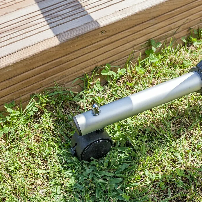 Gre Planenaufroller - Passend für: Pools bis 500 cm Breite - Nahaufnahme des silbernen Metallbeins mit schwarzer Rolle, das unter einer Holzterrasse auf Rasen steht.